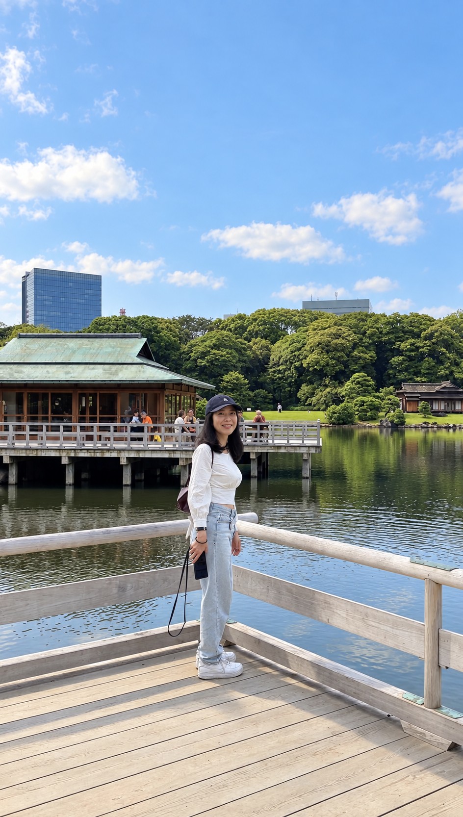 Hitomy standing beside a wooden railing in a sunny Japanese garden