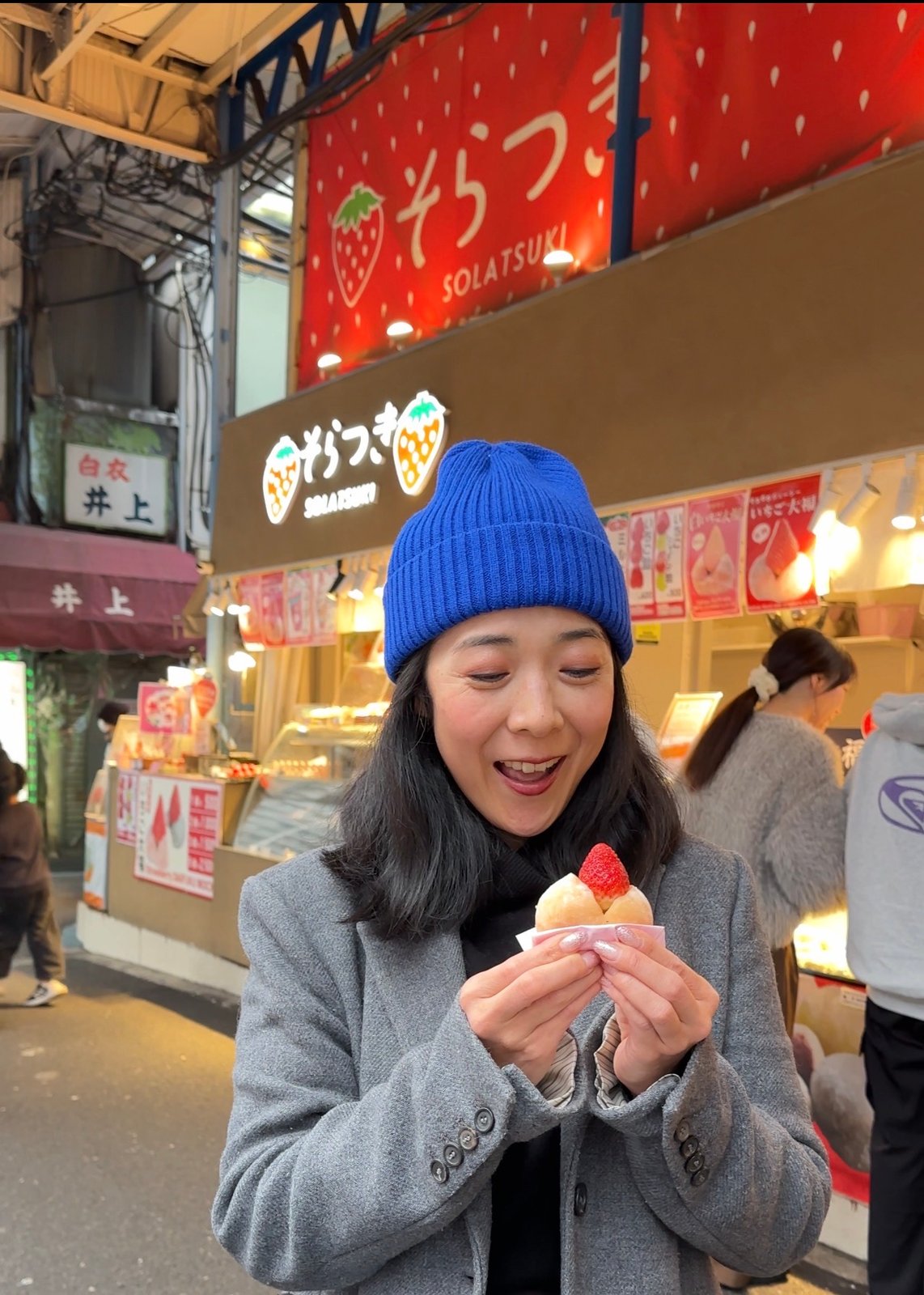 Hitomy enjoying a strawberry daifuku at a market